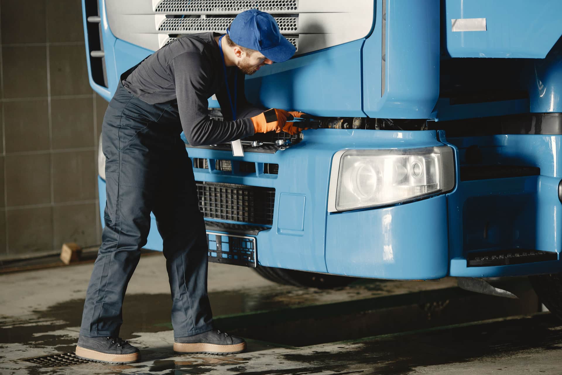 A mechanic inspects a truck's engine in a garage