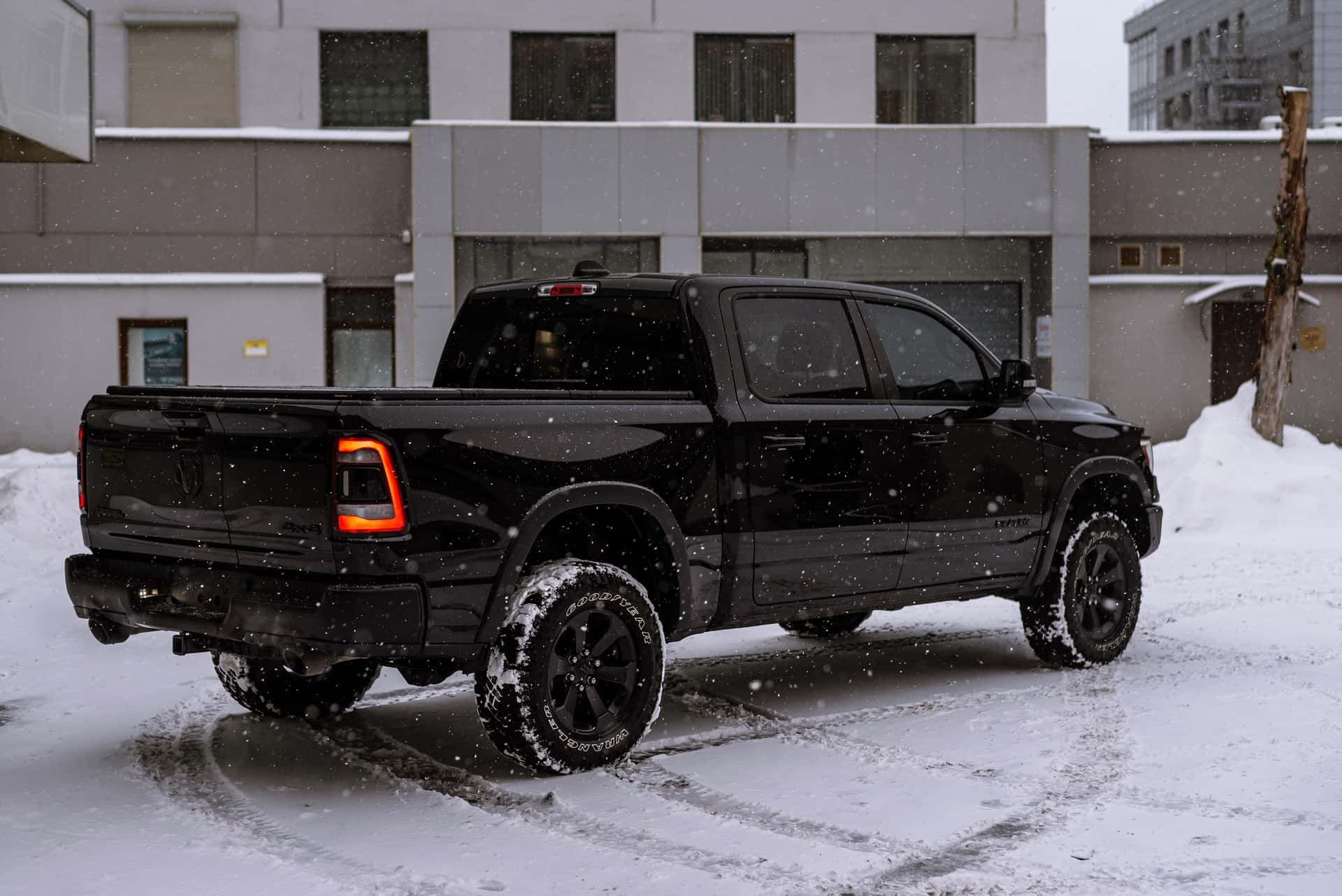 Black pickup truck parked on a snowy urban street during winter snowfall