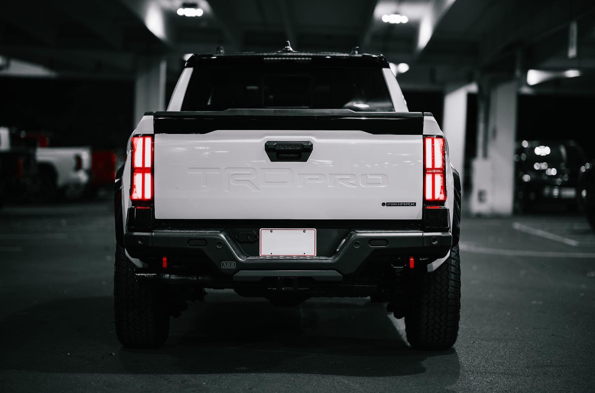 Rear view of a white pickup truck in a parking garage at night