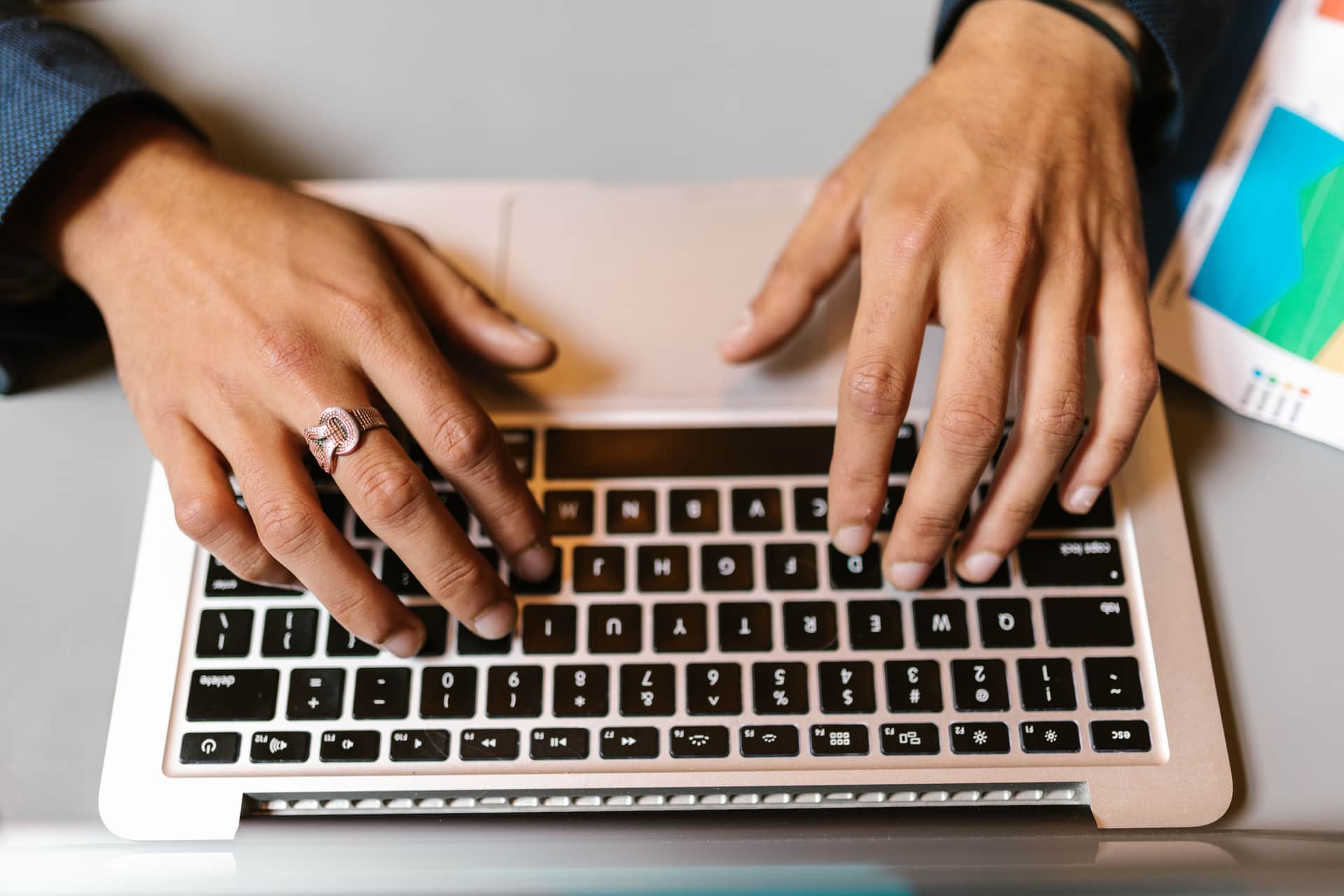 Hands typing on a laptop with a ring