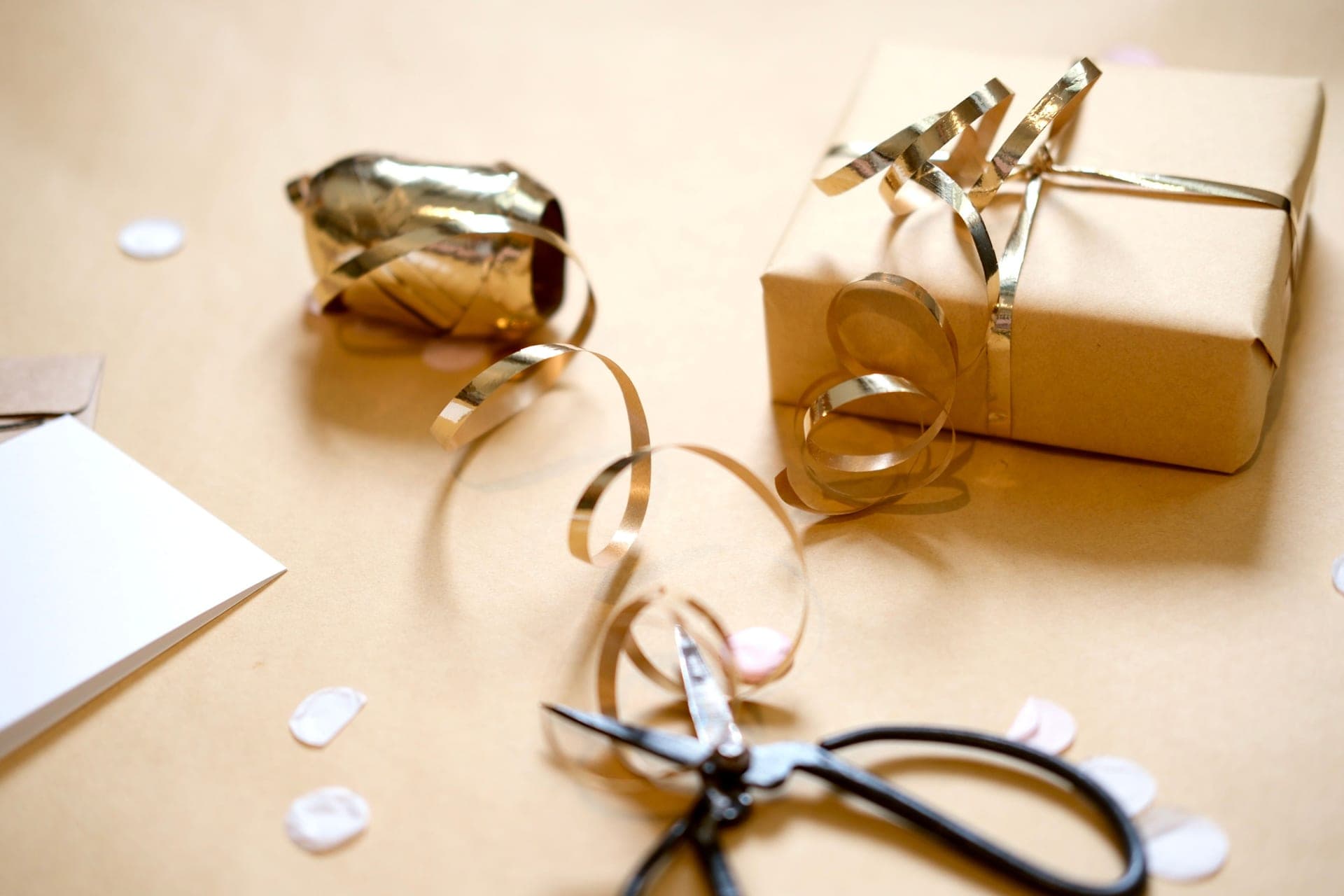 Brown paper gift with gold ribbon and scissors