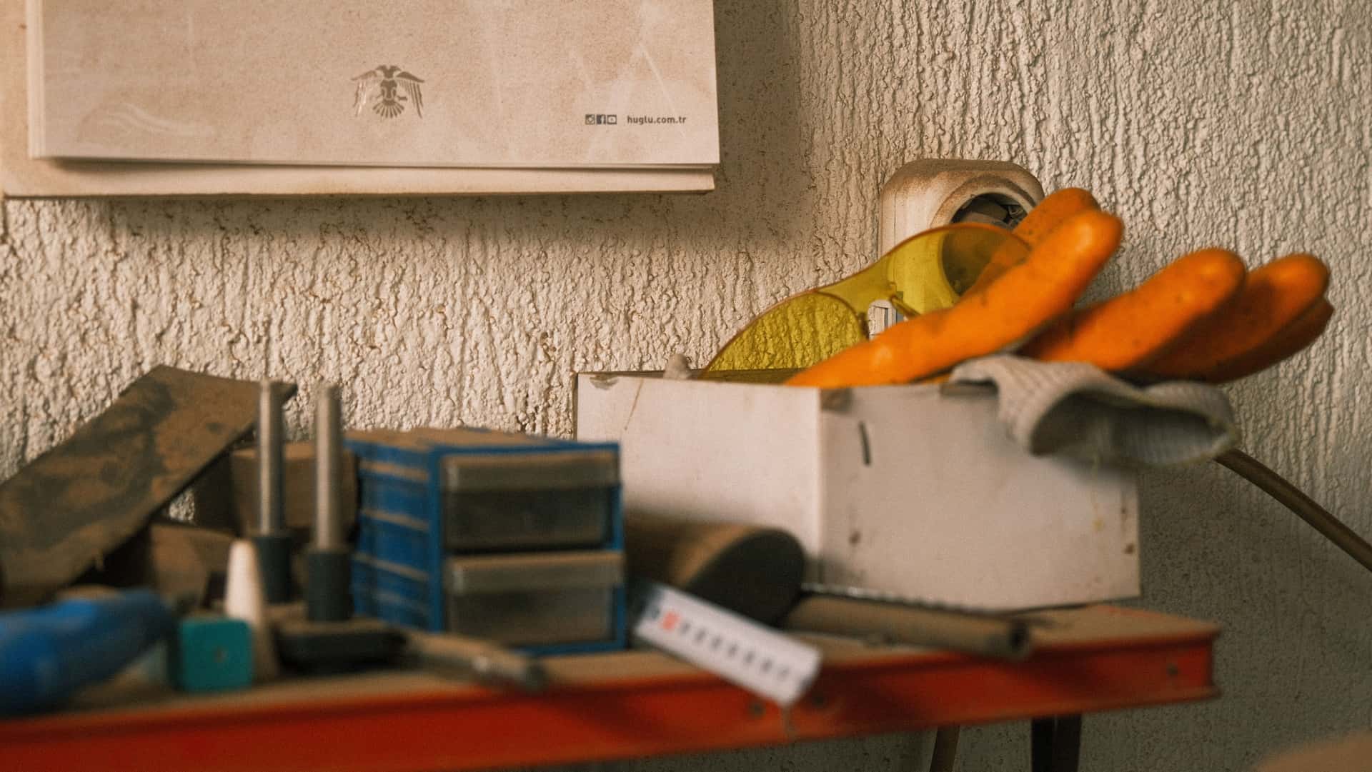 An organized workshop bench with tools, gloves, and storage boxes in a retro setting