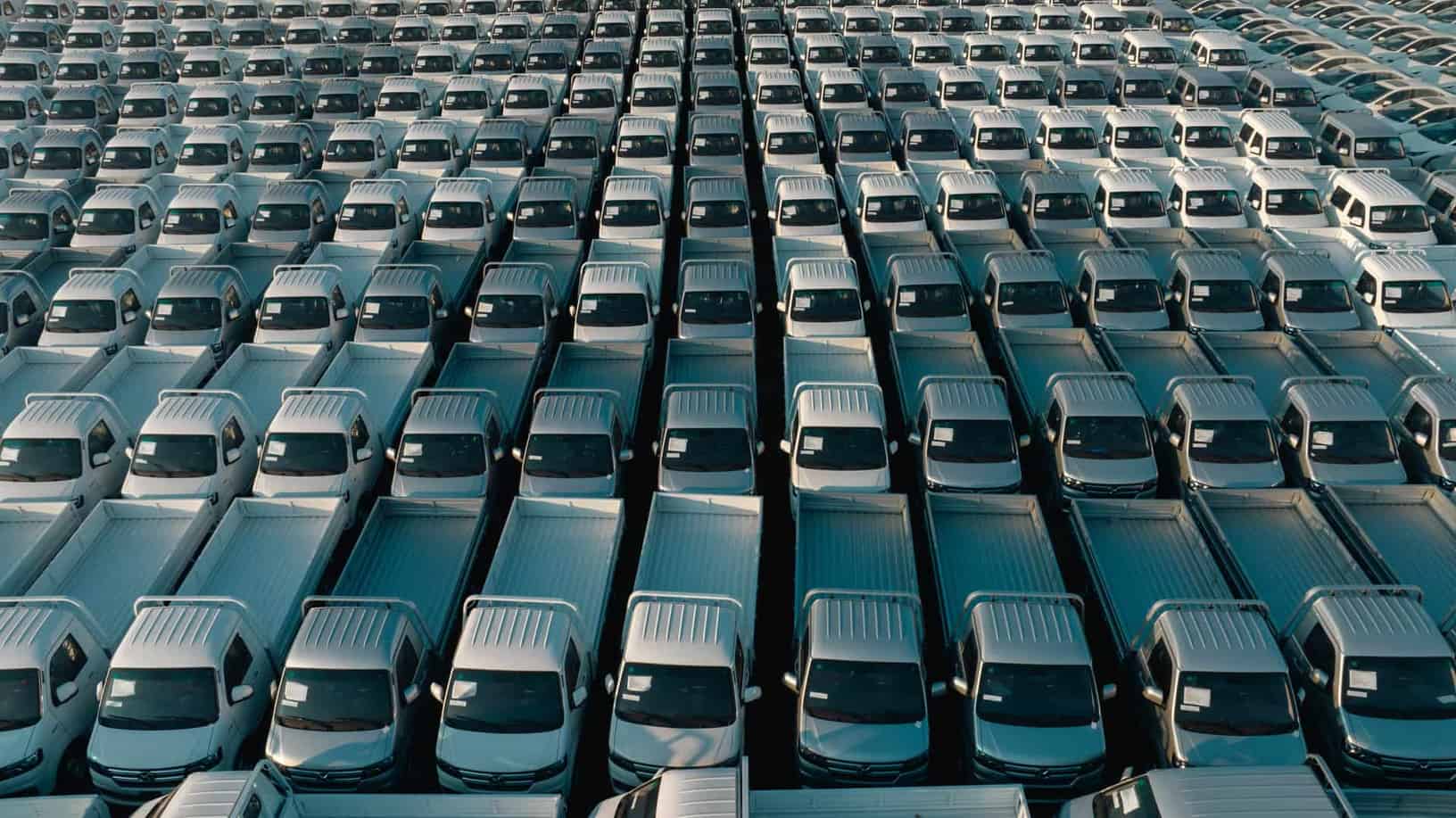Overhead shot of a large collection of white pickup trucks parked in neat rows