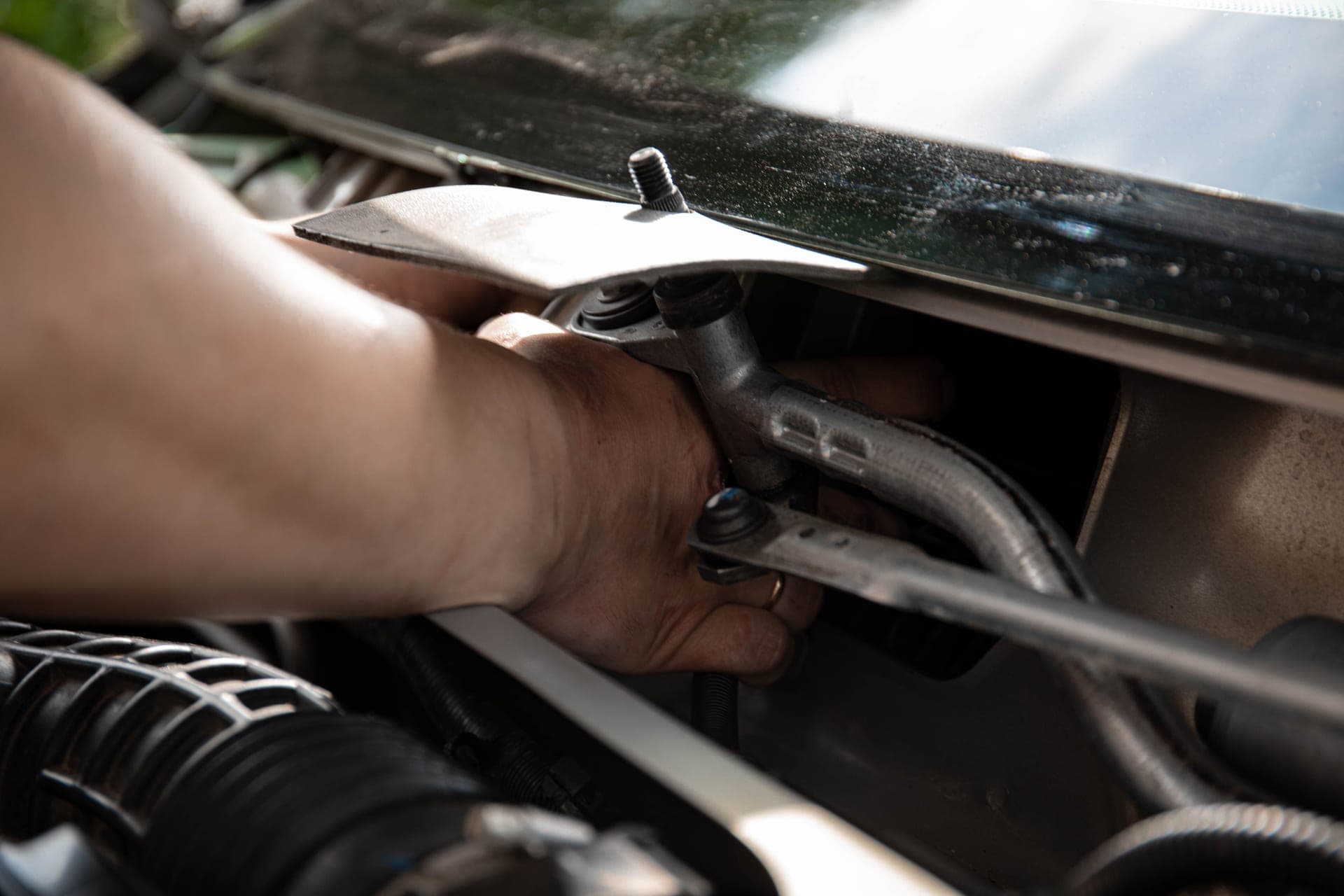 Close-up of a mechanic's hands working on car engine maintenance