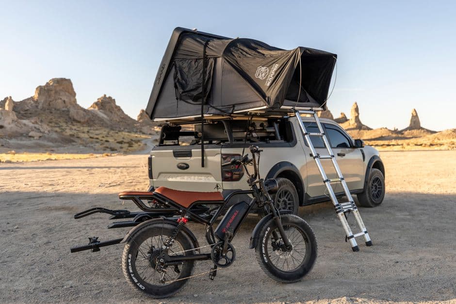 Truck with rooftop tent and mountain bike in desert landscape, perfect backdrop for an outdoor adventure