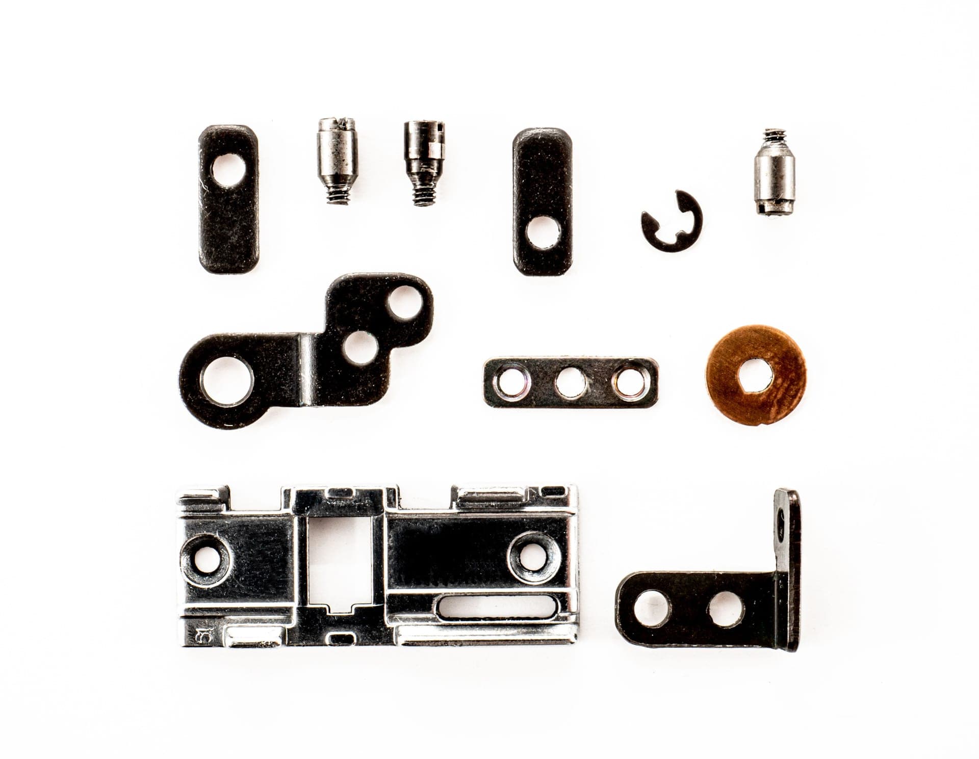 A top view of various metal fasteners arranged on a white background