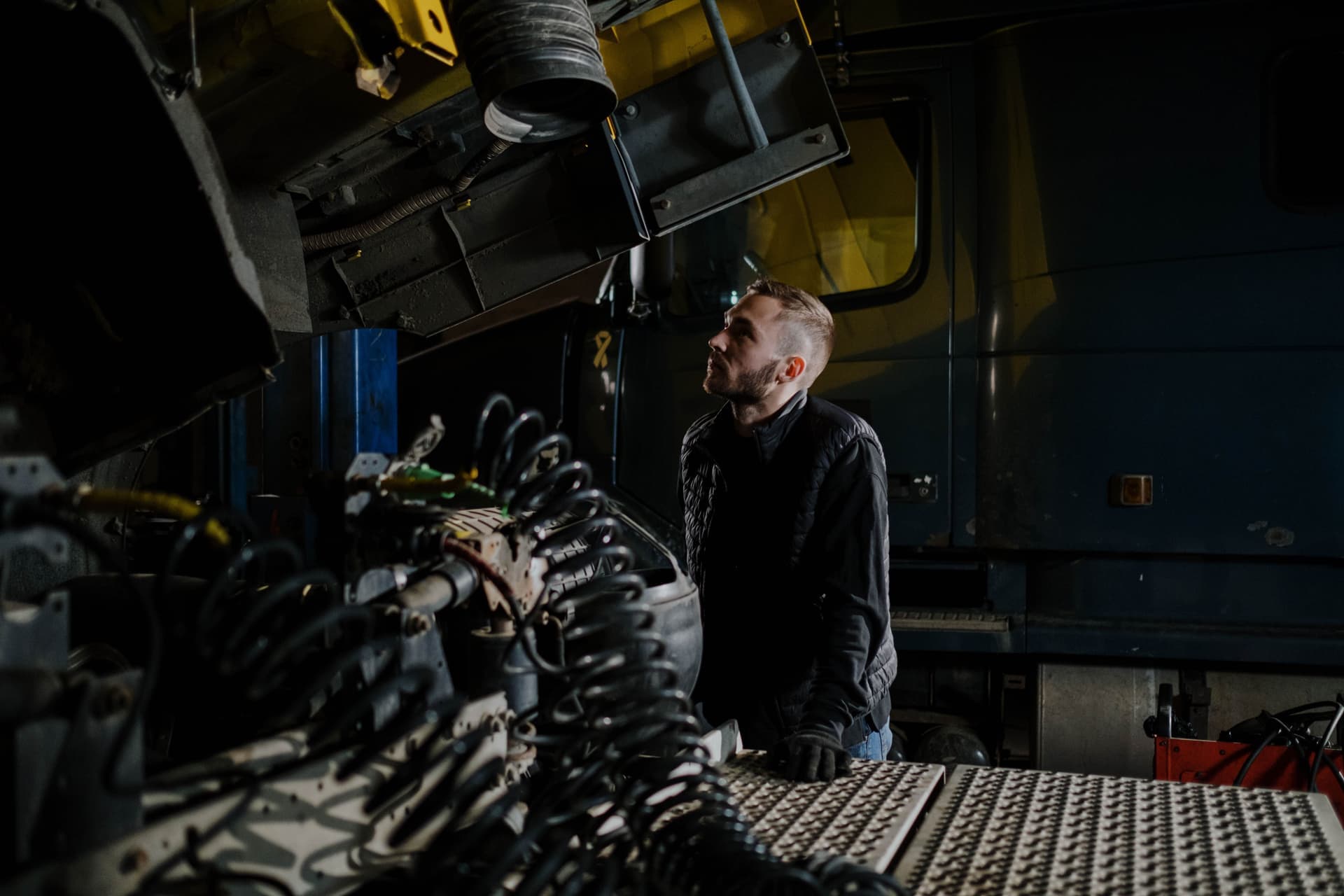 A truck mechanic carefully examines an engine inside a garage shop