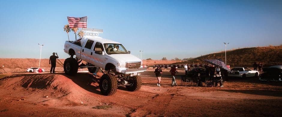 A lifted truck at an off-road adventure event during sunset, capturing excitement and community spirit