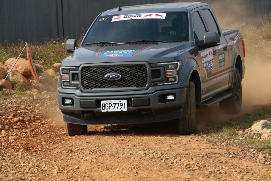Gray Ford F150 driving fast on a rocky dirt road during an offroad adventure race