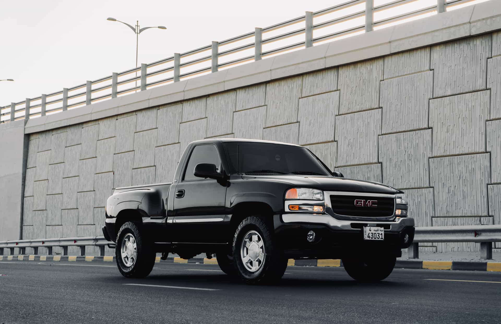 Sleek black pickup truck parked on an urban road under a concrete overpass in daylight