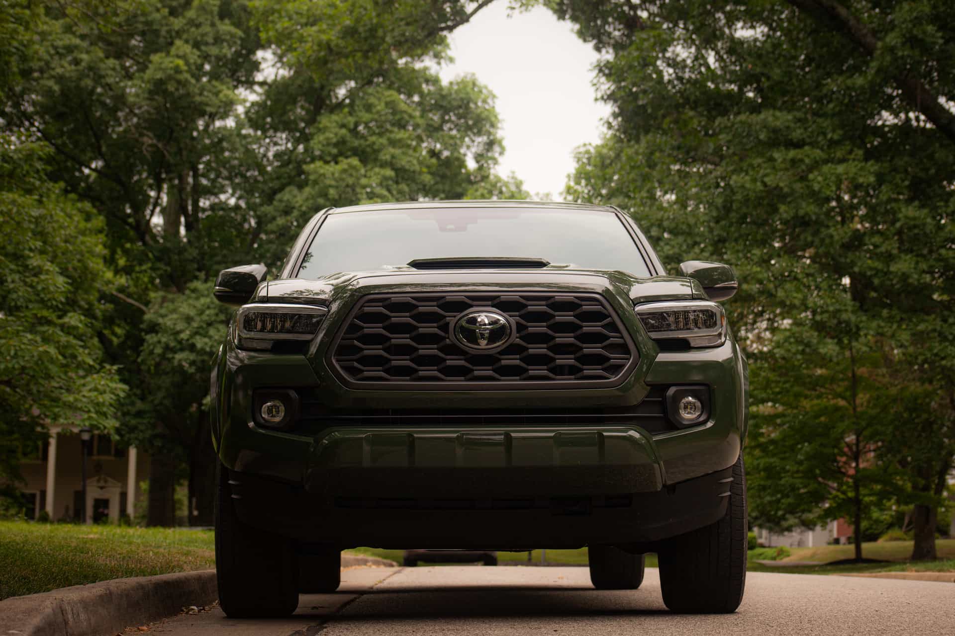 Green Toyota Tacoma truck parked outdoors under trees on a suburban street