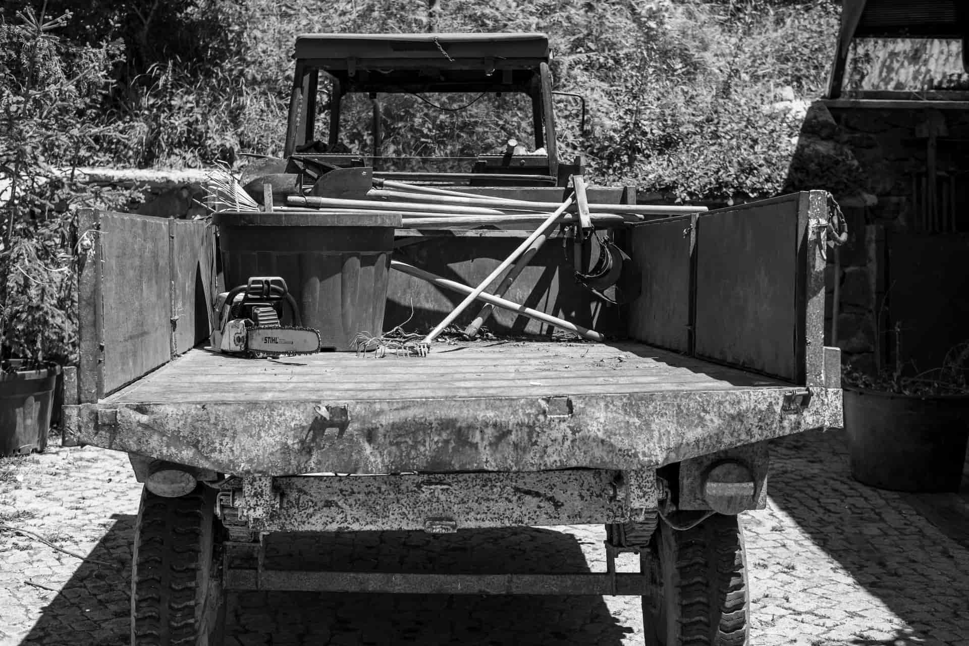 Black and white image of a vintage truck bed filled with rustic tools