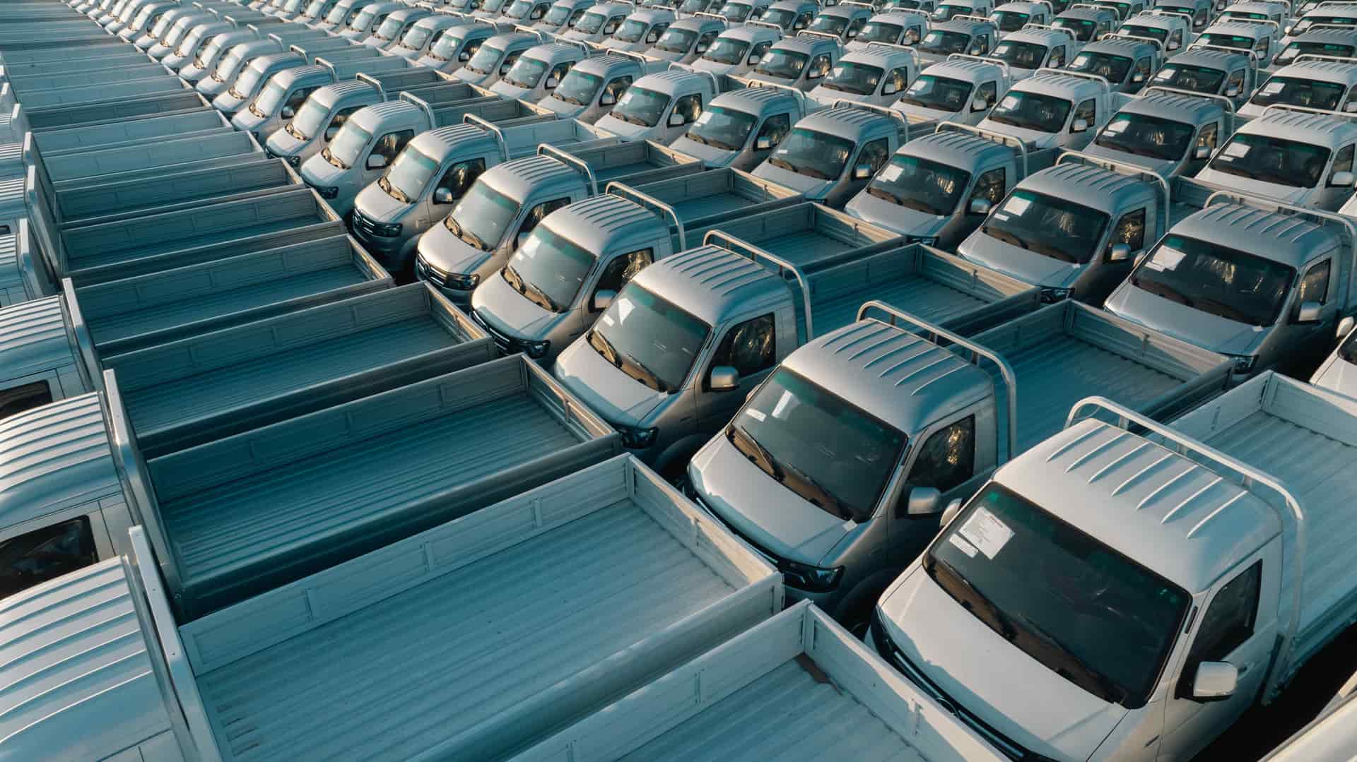 Aerial shot of multiple silver pickup trucks aligned in rows