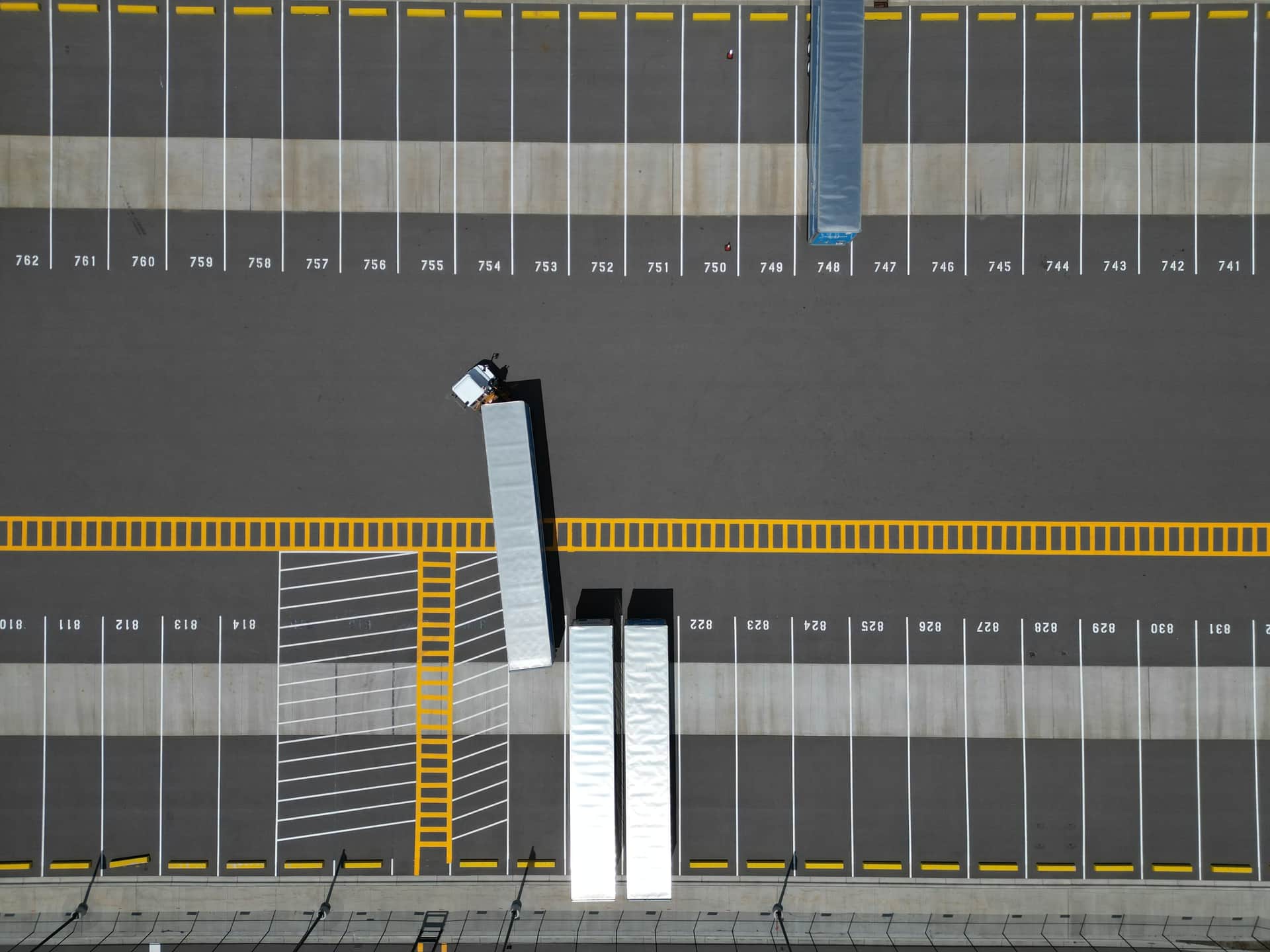 An aerial view of a large parking lot with lined spaces and semi-trucks