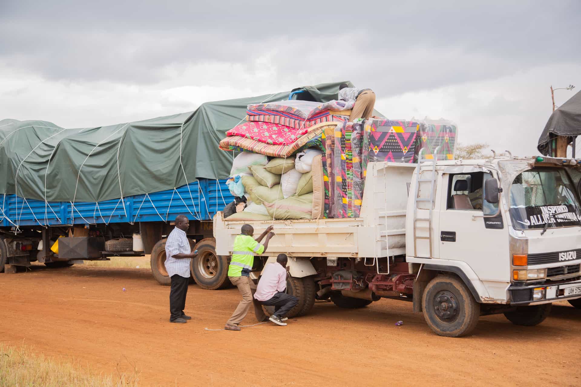People loading supplies onto a truck in a rural area under cloudy skies